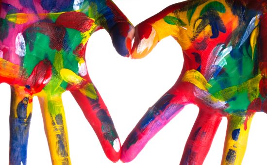 two painted colorful hands forming a heart on a white background