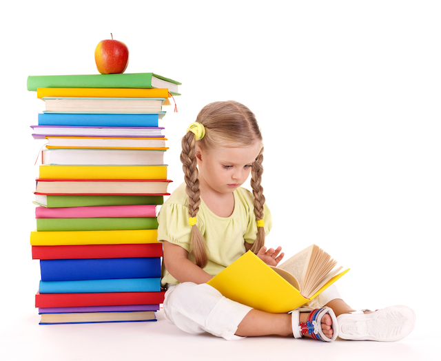 Little girl next to stack of books reading